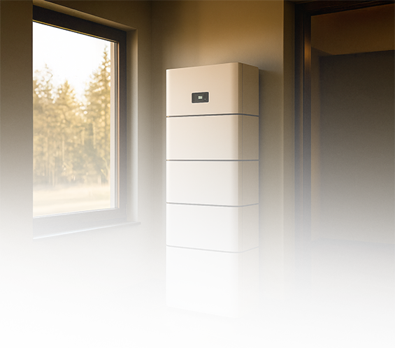 Ein moderner weißer Batteriespeicher steht an einer Wand in einem sonnendurchfluteten Raum mit einem großen Fenster und einem gefliesten Boden, der den Blick auf die Bäume draußen freigibt.