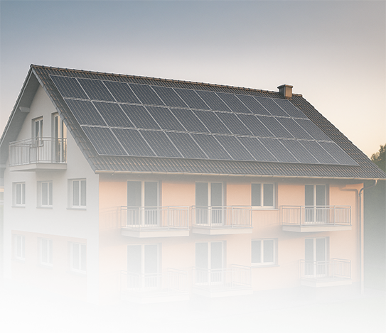 Ein modernes, zweistöckiges Wohnhaus mit orangefarbenen und weißen Wänden, mehreren Balkonen und einem mit Sonnenkollektoren bedeckten Dach, fotografiert bei Sonnenuntergang.